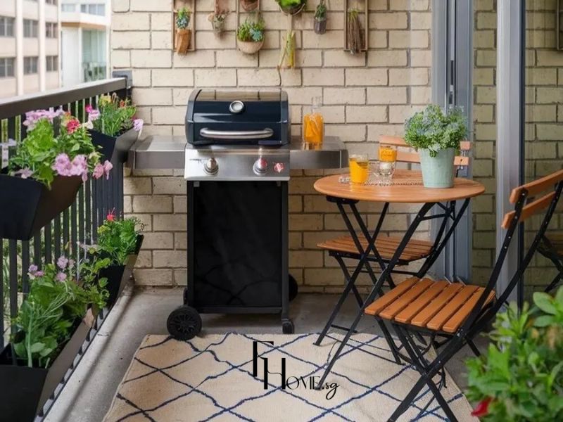 Ban công chung cư 50m2 với bàn tròn gỗ tự nhiên, ghế gấp khung sắt đen và chậu hoa treo tường tạo góc cà phê ngoài trời