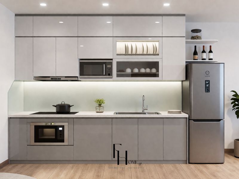 Bố trí không gian mở chung cư 55m2 với hệ tủ chữ I tích hợp lò nướng và lò vi sóng âm tường, kính ốp tường xanh bạc hà và đèn hắt chiếu sáng mặt bếp