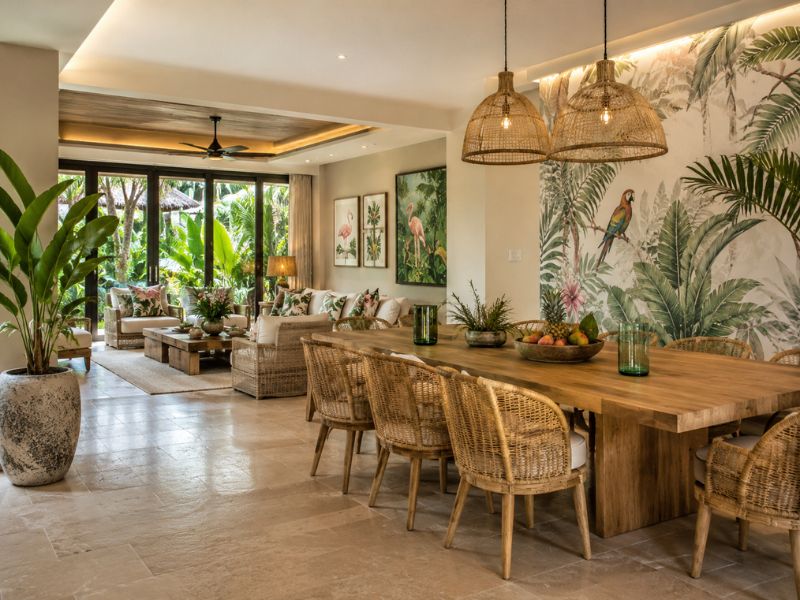 Không gian bàn ăn và phòng khách phong cách Tropical với tranh tường họa tiết lá nhiệt đới, ghế mây và bàn gỗ lớn