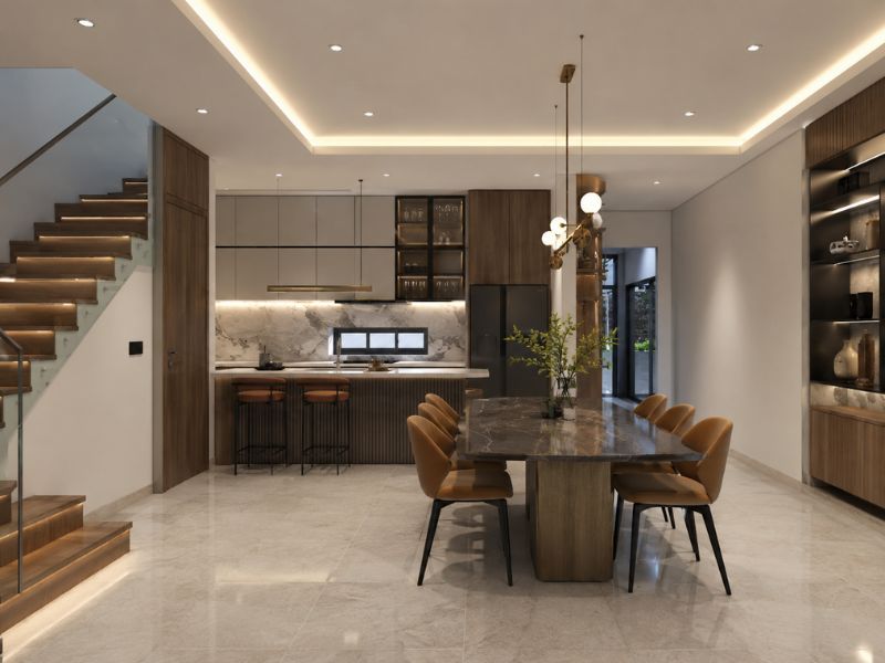 Khu bàn ăn liền bếp phong cách thiết kế nội thất chung cư đương đại với bàn ăn mặt đá, tủ bếp gỗ tối màu và hệ đèn thả trang trí