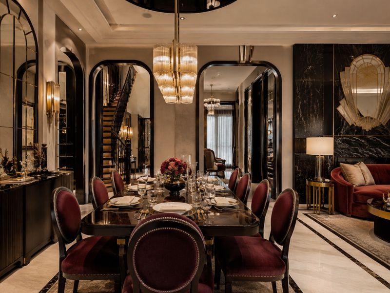 Phòng ăn phong cách thiết kế nội thất Art Deco với bàn ăn đen bóng, ghế nhung đỏ rượu, vòm trang trí, đèn treo hình học và mảng tường đá tối màu