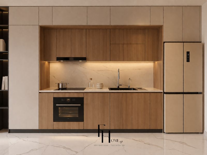 Phòng bếp chung cư 55m2 bố cục chữ I toàn bộ gỗ walnut nâu ấm, ốp tường đá vân trắng vàng và đèn hắt chiếu sáng mặt bếp
