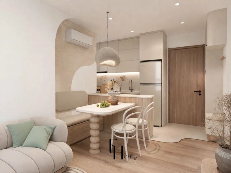 Góc bếp liền bàn ăn chung cư 68m2 Japandi với mảng tường vòm thạch cao be cát, bàn ăn chân cột tròn trắng và đèn thả cầu vải be 