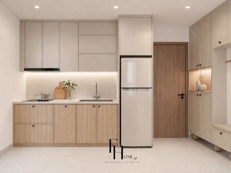 Bếp chung cư 68m2 Japandi tủ be mờ và gỗ sồi phân tầng, đèn dải chiếu sáng mặt bàn đá trắng, tủ lạnh âm tường giữ mặt tiền bếp phẳng