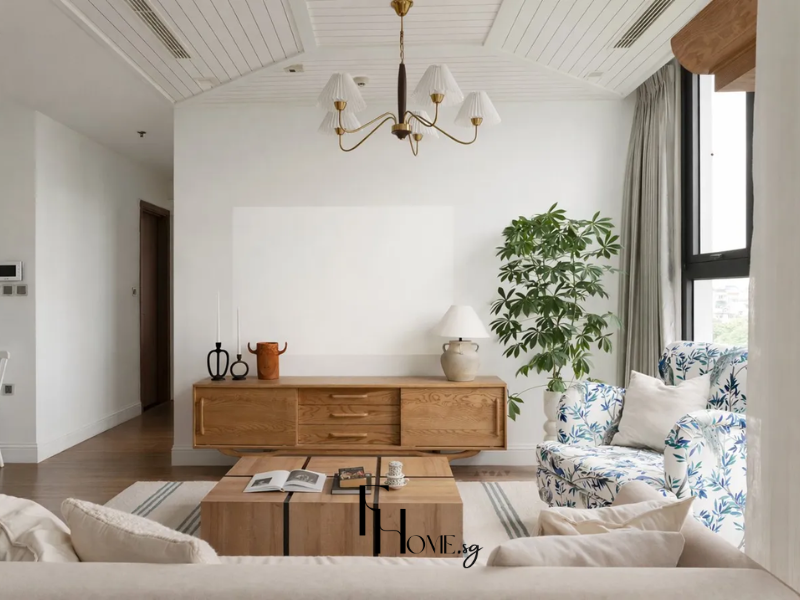 Phòng khách chung cư 50m2 phong cách Địa Trung Hải với trần lanh tô gỗ trắng, đèn chùm đồng 6 nhánh, sofa vải linen trắng kem và ghế đơn họa tiết cành lá xanh coban