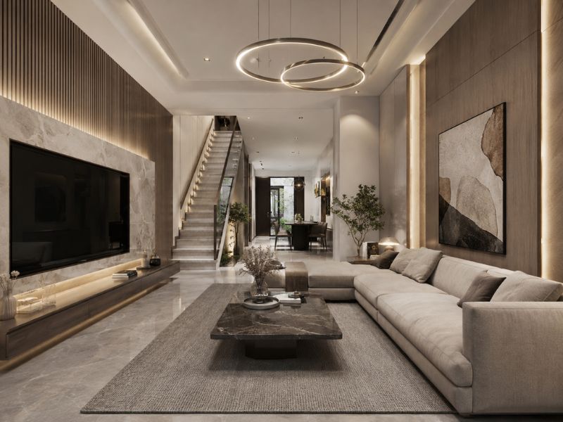 Phòng khách nhà phố phong cách đương đại với sofa lớn, bàn trà mặt đá, đèn thả trần hiện đại và cầu thang thẳng phía sau