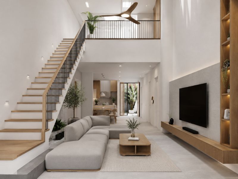 Phòng khách nhà phố phong cách tối giản với trần cao, cầu thang thẳng, sofa chữ L và nội thất gỗ sáng màu