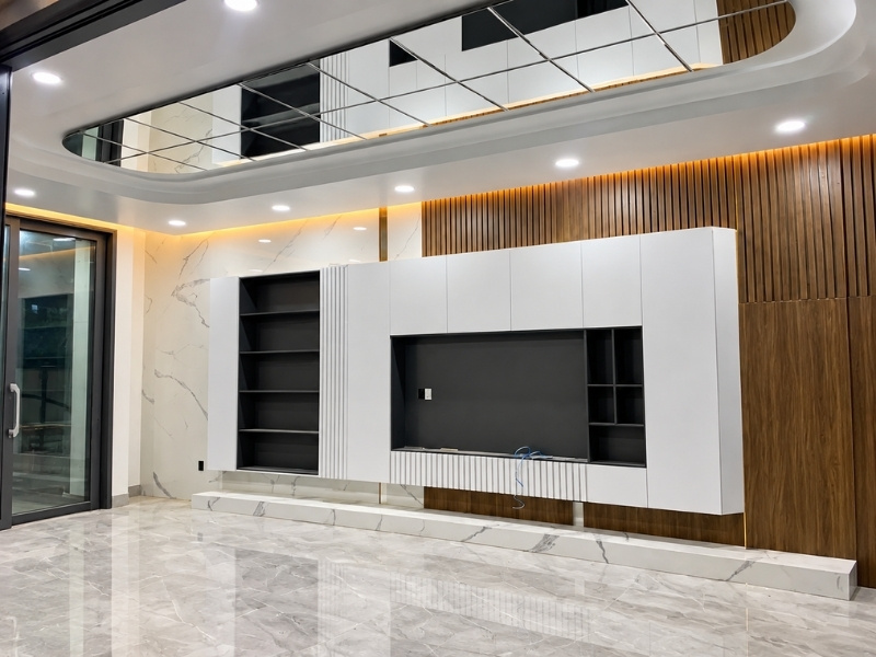Phòng khách với trần ốp gương ghép phản chiếu ánh sáng và hệ tủ tivi lam gỗ sang trọng