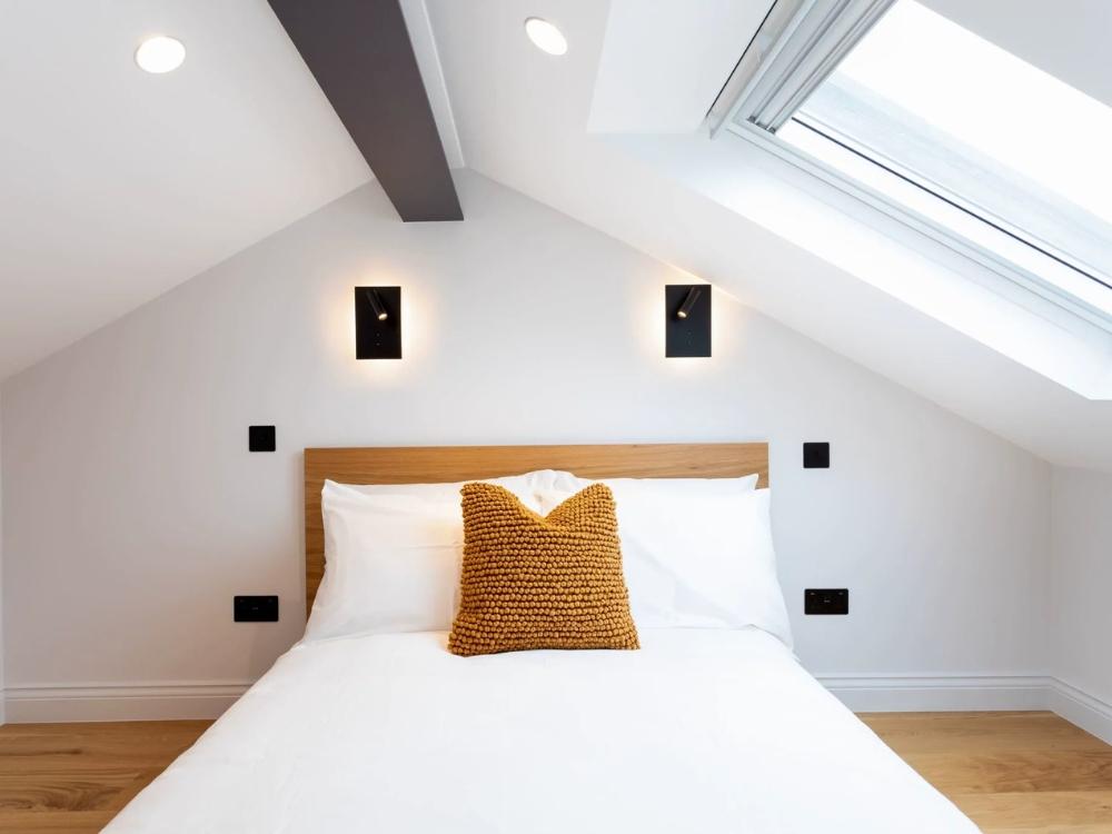 Phòng ngủ bố trí giường cỡ queen với đầu giường tích hợp kệ sách và ổ cắm điện tiện lợi.