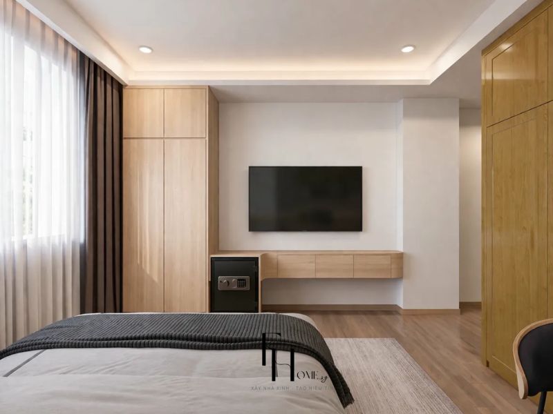 Phòng ngủ chung cư 55m2 phong cách hiện đại với tủ gỗ sáng, tivi treo tường và kệ gỗ treo tích hợp két sắt
