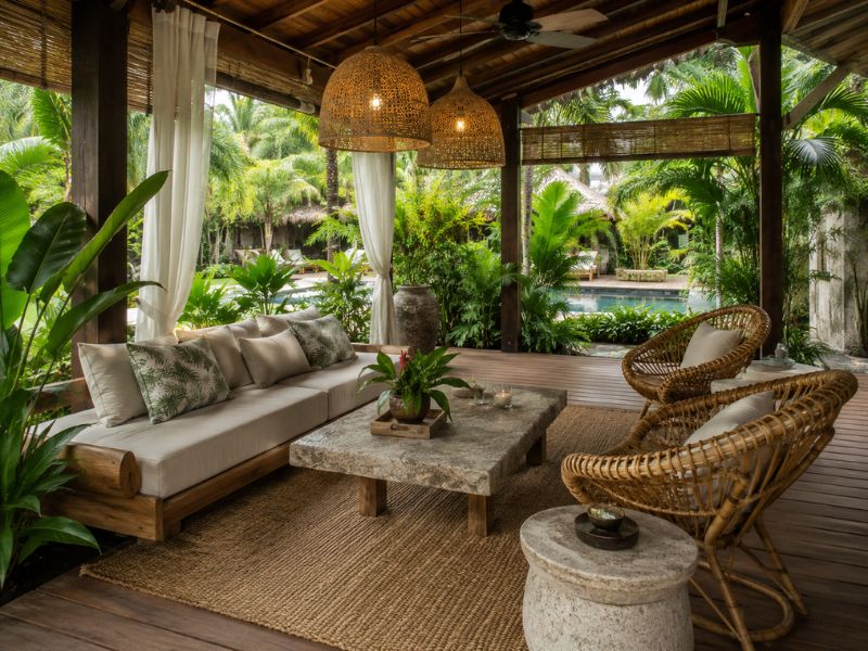Phòng tắm phong cách Tropical với lavabo đá, tủ gỗ, thảm cói và mảng cây xanh sau vách kính