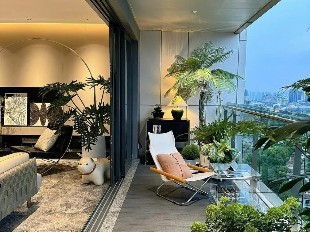 Ban công chung cư với cây xanh, ghế ngồi và bàn nhỏ tạo không gian thư giãn thoải mái và gần gũi với thiên nhiên.