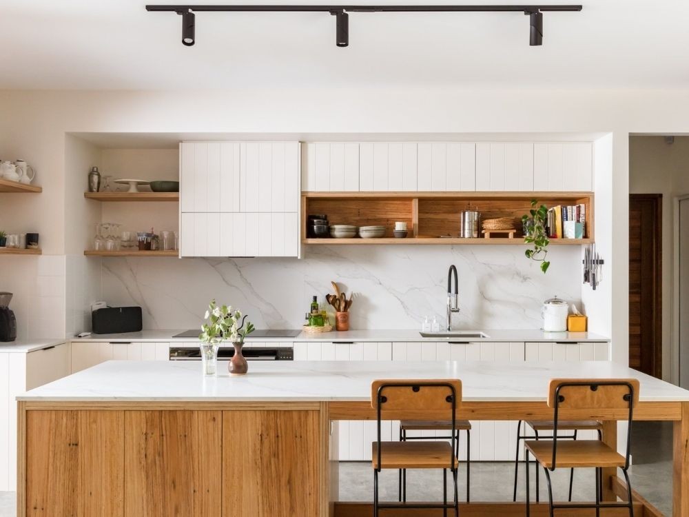 Bếp Japandi sáng thoáng, mặt đá trắng vân nhẹ, kệ mở gỗ tự nhiên và bàn ăn nối liền