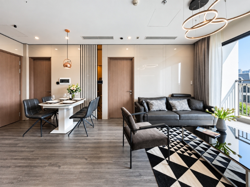 Không gian sinh hoạt chung căn hộ 3 phòng ngủ cho thuê với sofa xám, bàn ăn và thảm hình học