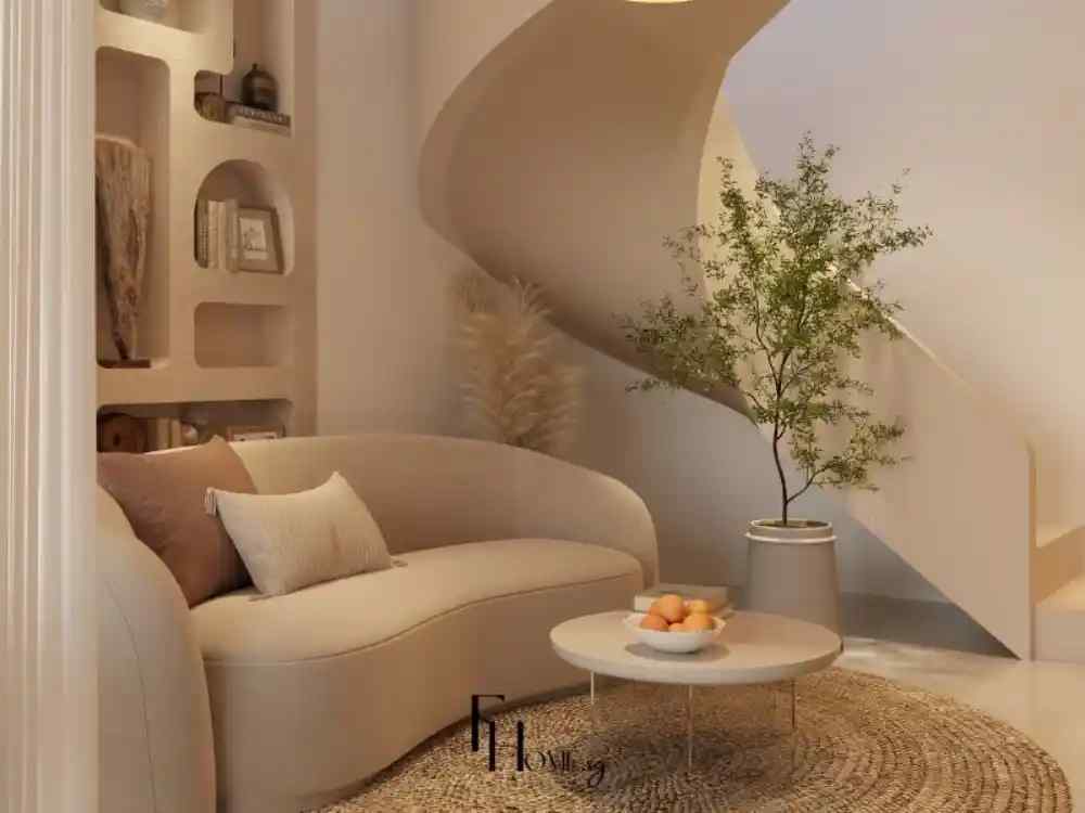 Góc phòng khách phong cách organic với sofa cong be nhạt, bàn tròn thấp và cây xanh bên cầu thang bo tròn