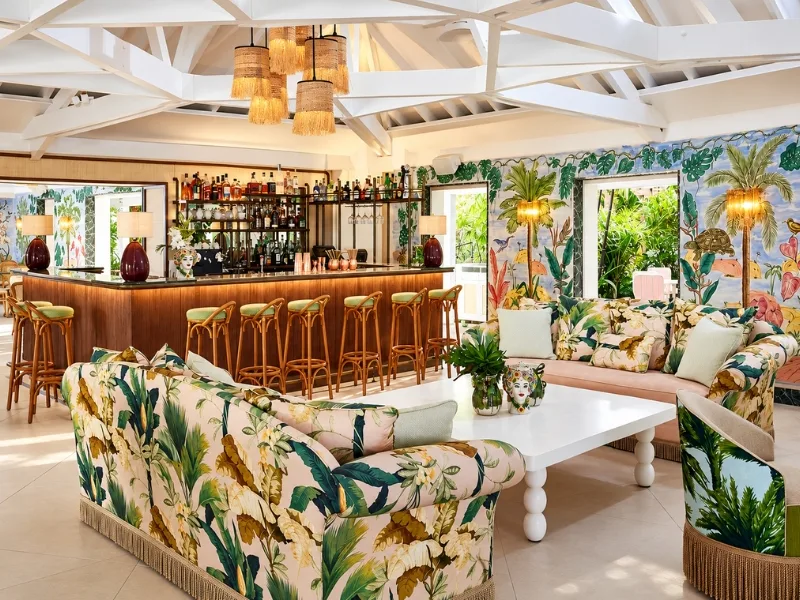 Khu ngồi phong cách Tropical bố trí ghế họa tiết lá cạnh quầy bar gỗ hướng ra khoảng xanh ngoài trời.
