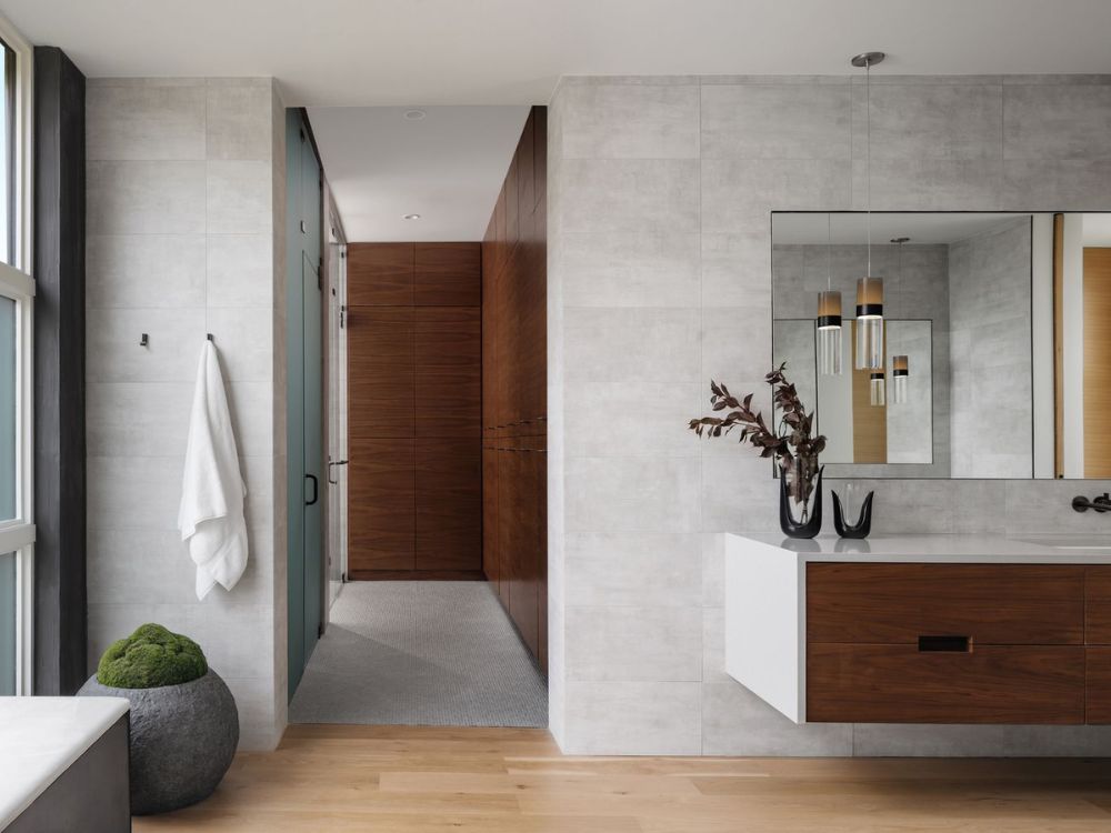 Nhà tắm Japandi rộng thoáng với tường xi măng sáng, tủ gỗ nâu và đèn treo tinh tế