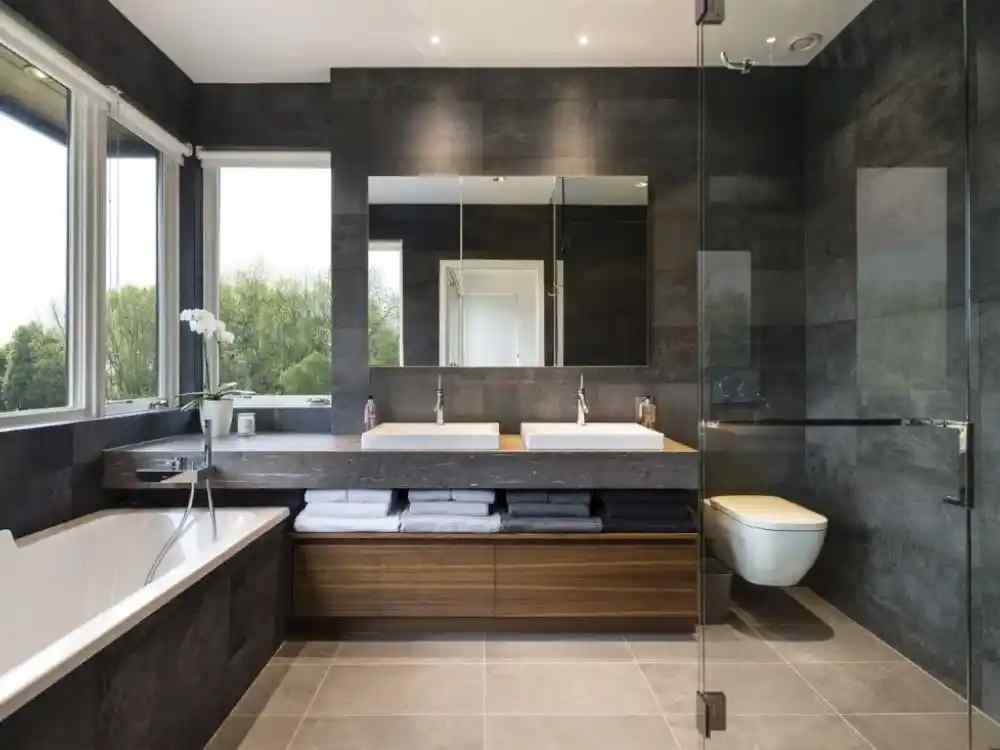 Nhà vệ sinh tối giản với tông xám đen, gương tròn phát sáng và chậu rửa đen nhám