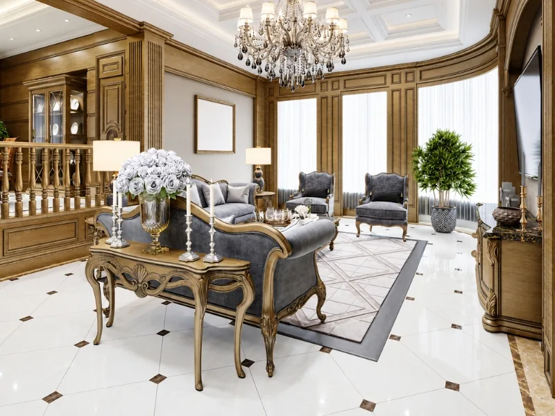 Nội thất phòng khách phong cách cổ điển sử dụng bàn ghế chạm khắc và vách ốp gỗ dưới đèn chùm pha lê.