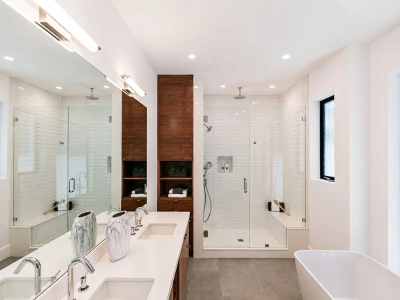 Thiết kế phòng tắm phong cách hiện đại kết hợp tủ lavabo trắng với khu tắm ngăn bằng kính trong.
