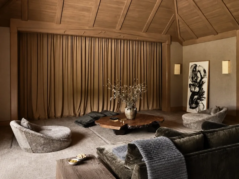 Không gian sinh hoạt phong cách Wabi Sabi có trần dốc phủ vật liệu đan cùng rèm nâu và ghế ngồi thấp.