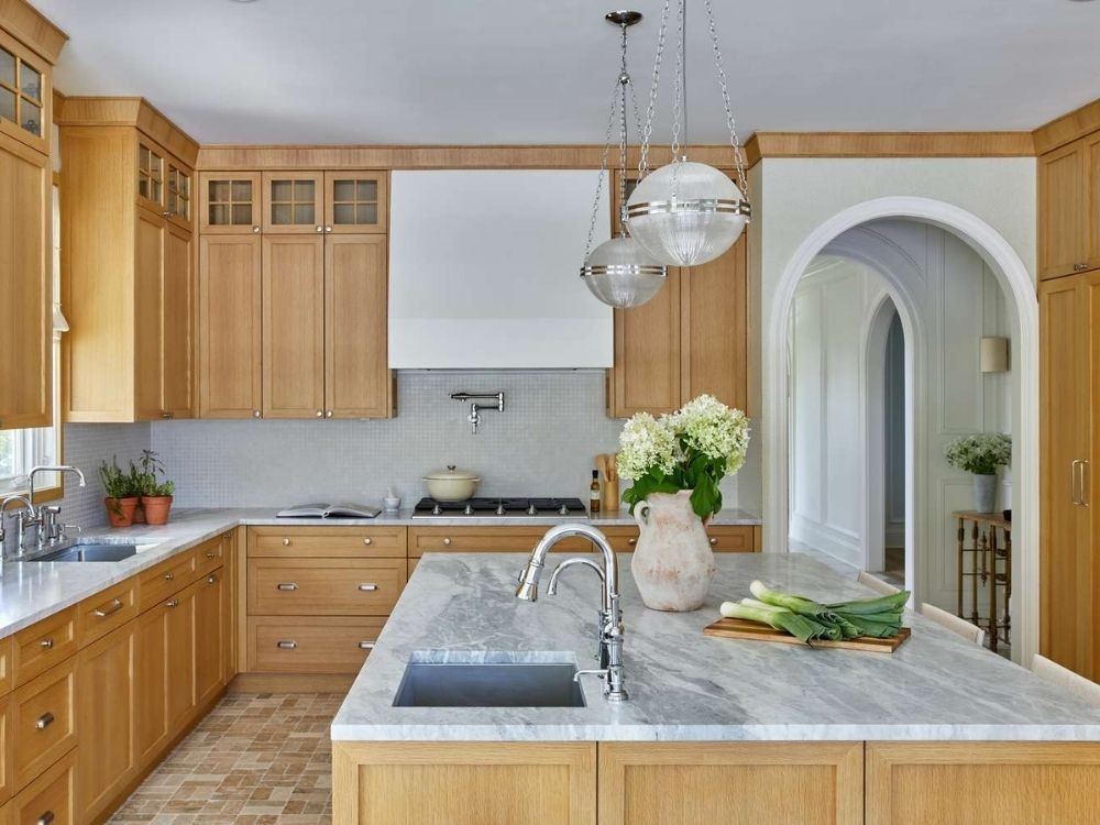 Phòng bếp cổ điển gỗ sáng, đảo bếp mặt đá marble, tay nắm kim loại đồng