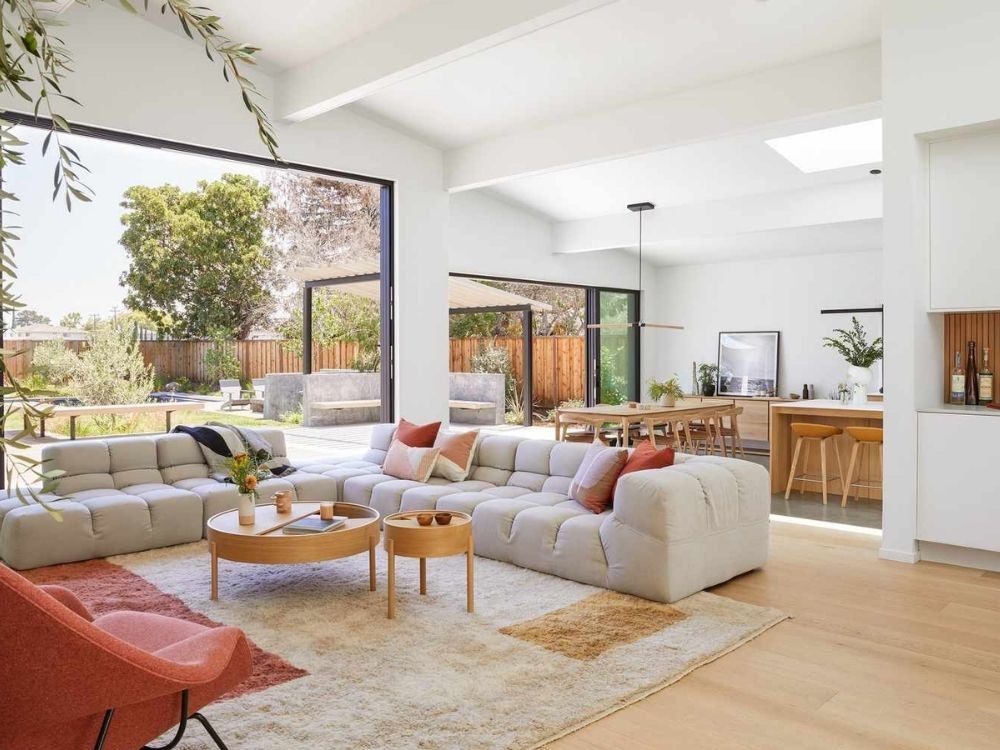 Phòng bếp liền phòng khách tông sáng tự nhiên, sofa modular thấp, bàn tròn gỗ