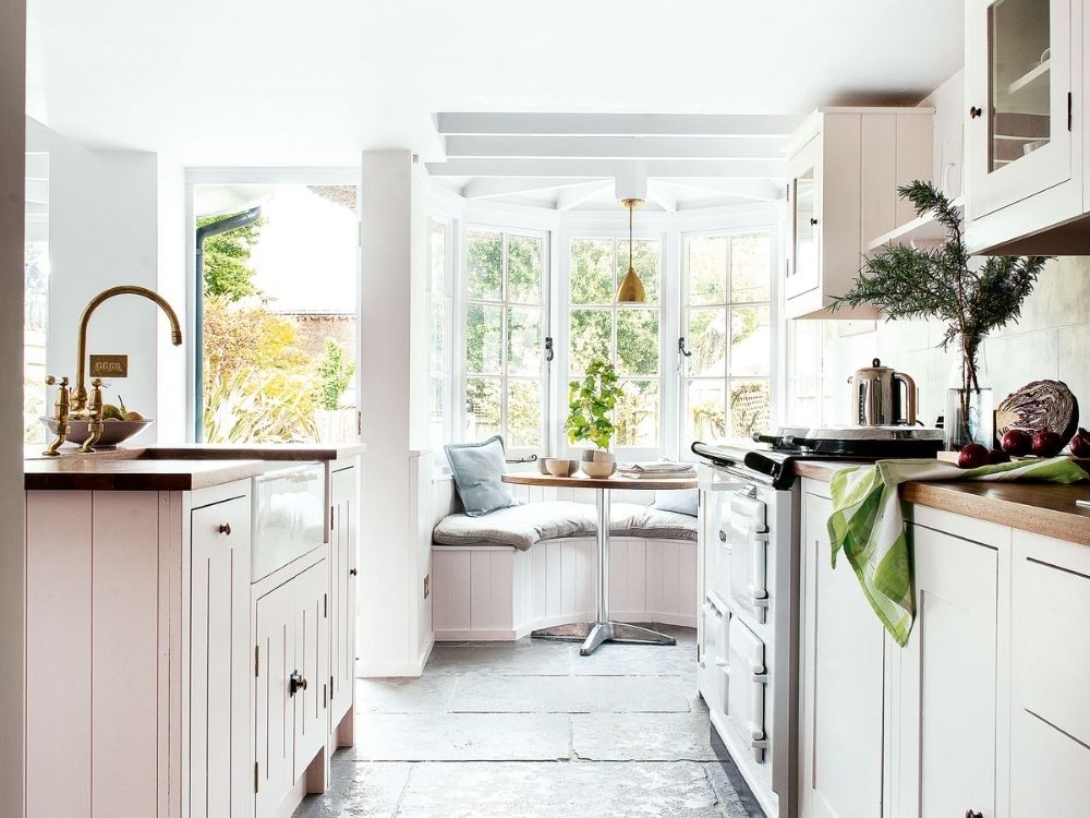 Phòng bếp sáng tự nhiên với tủ trắng, mặt gỗ ấm, cửa sổ lớn đón nắng