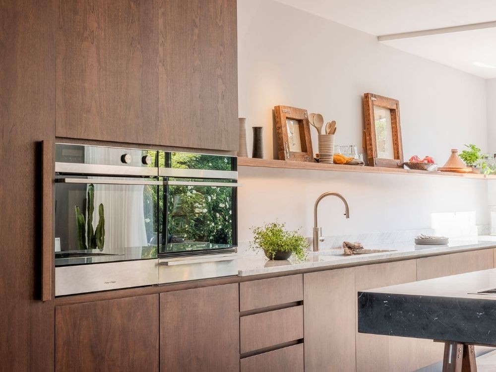 Phòng bếp tủ bếp chữ I gỗ nâu, kệ gỗ treo dài, mặt đá sáng