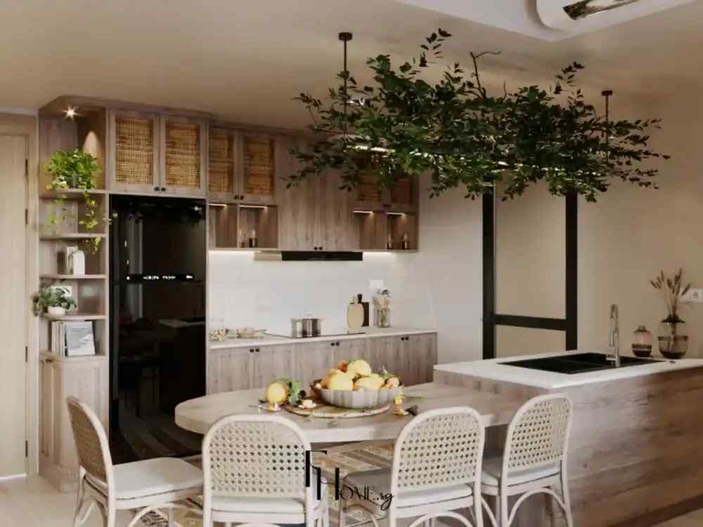 Phòng bếp với tủ bếp gỗ sáng, mặt bếp trắng, bàn ăn liền đảo bếp, ghế mây, chùm cây xanh