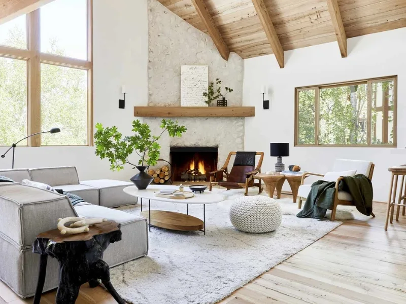 Phòng khách phong cách Bắc Âu có sofa sáng màu cùng lò sưởi dưới trần dốc để lộ dầm gỗ.