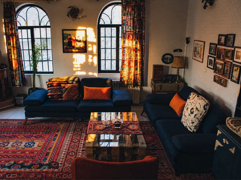 Phòng khách phong cách Bohemian phối sofa xanh đậm với thảm thổ cẩm và đèn lồng nhiều màu.