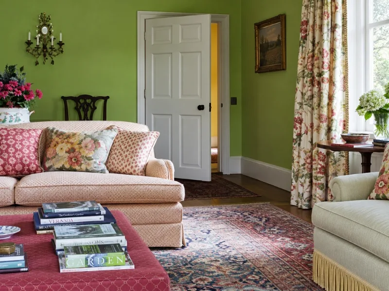 Phòng khách phong cách Farmhouse kết hợp sofa hồng nhạt với rèm hoa trên nền tường xanh lá.