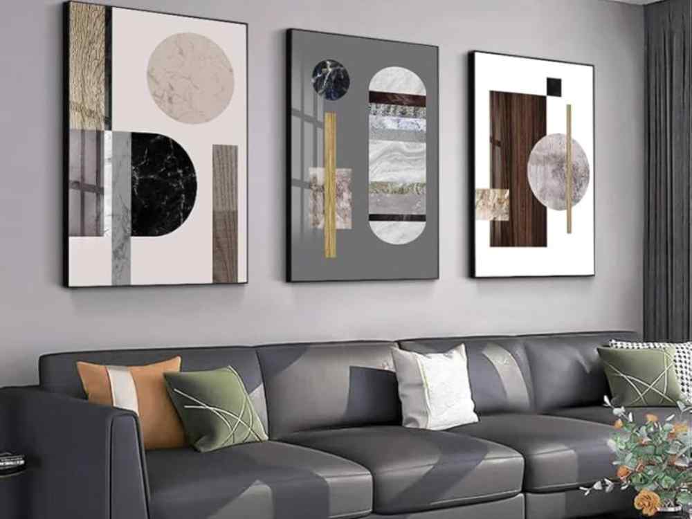 Phòng khách hiện đại với sofa da xám, tranh treo tường hình học trừu tượng và ánh sáng tự nhiên