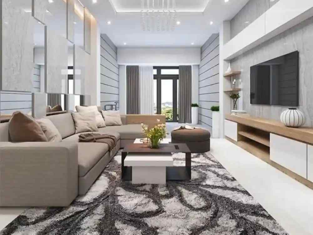 Phòng khách nhà ống hiện đại với sofa chữ L màu be, thảm lông xám và kệ TV ốp gỗ sáng