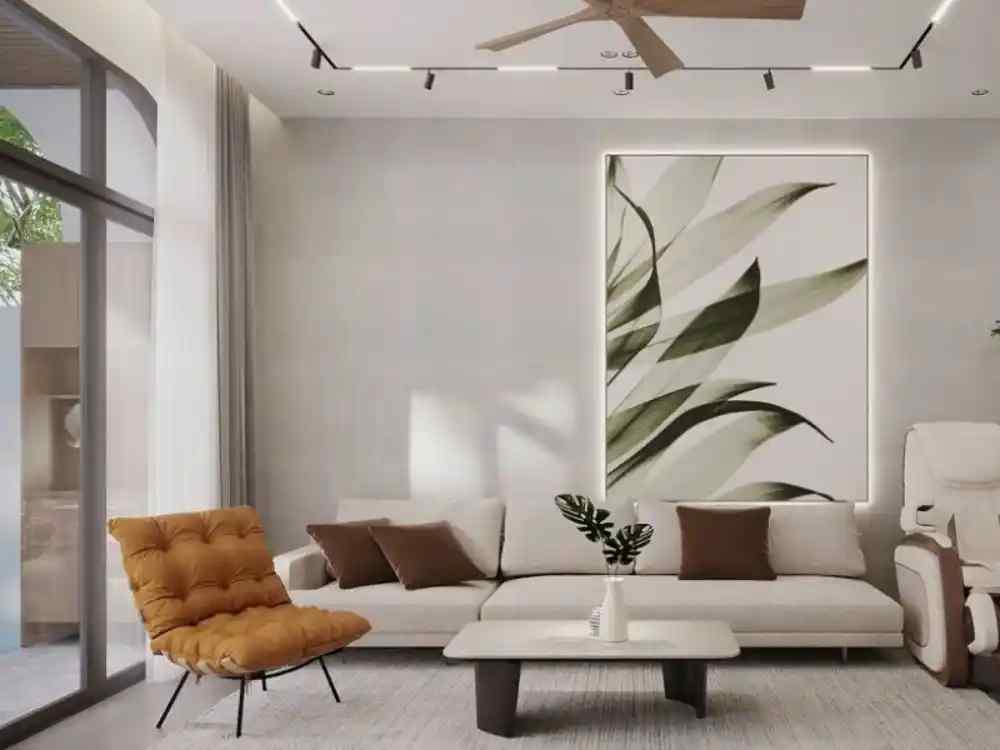 Phòng khách nhà ống phong cách tự nhiên với sofa kem, tranh lá lớn và ghế tựa da màu nâu cam cạnh cửa kính lớn