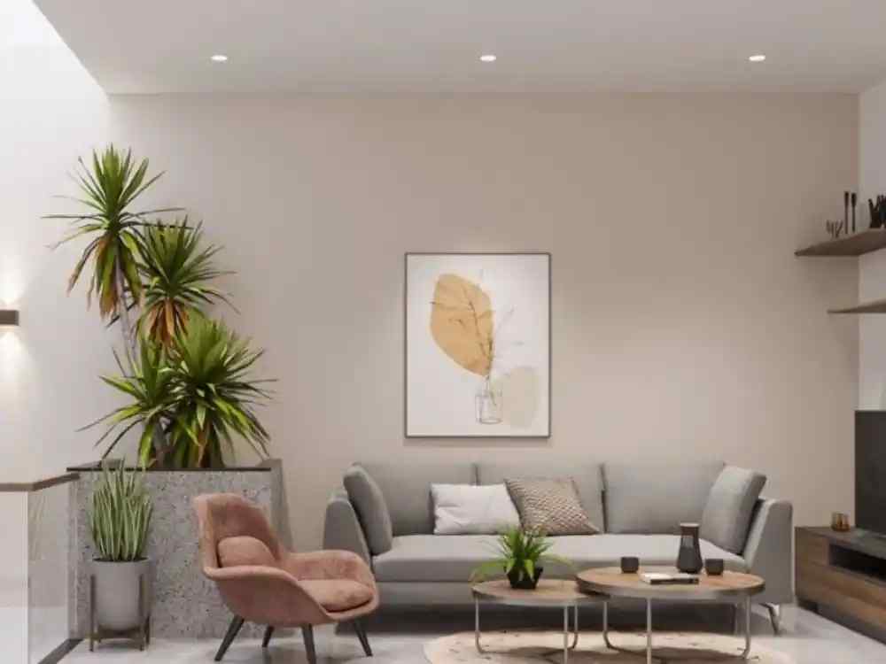 Phòng khách nhà ống tông be sáng với sofa xám, ghế đơn nhung nâu và cây xanh trang trí góc phòng