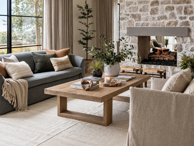 Phòng khách phong cách Rustic bố trí sofa xám cùng bàn trà gỗ dày cạnh lò sưởi ốp đá.