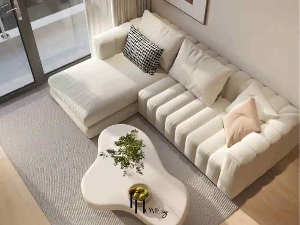 Phòng khách sáng với sofa kem chữ L, bàn trà trắng dáng tự do và ánh sáng tự nhiên nhẹ nhàng