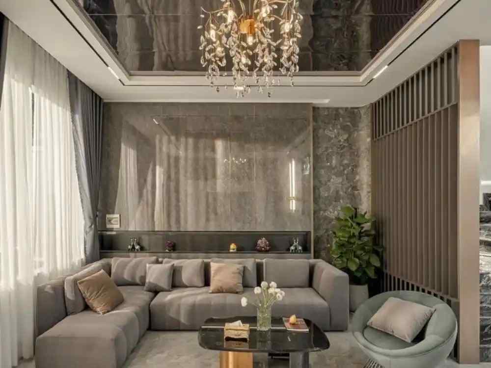 Phòng khách theo phong cách Luxury với ghế sofa bọc nhung ghi, tường đá xám và ánh sáng tự nhiên qua rèm trắng