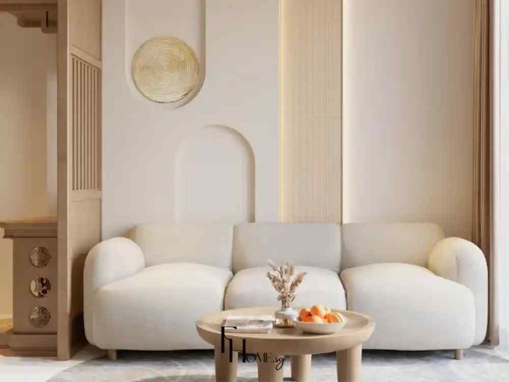 Phòng khách với sofa nỉ màu kem dáng bo tròn, bàn trà gỗ tròn nhỏ đặt giữa phòng