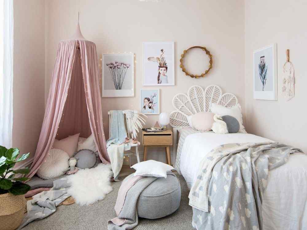 Phòng ngủ bé gái tông hồng pastel, giường mây trắng và lều vải mềm tạo góc đọc sách ấm cúng