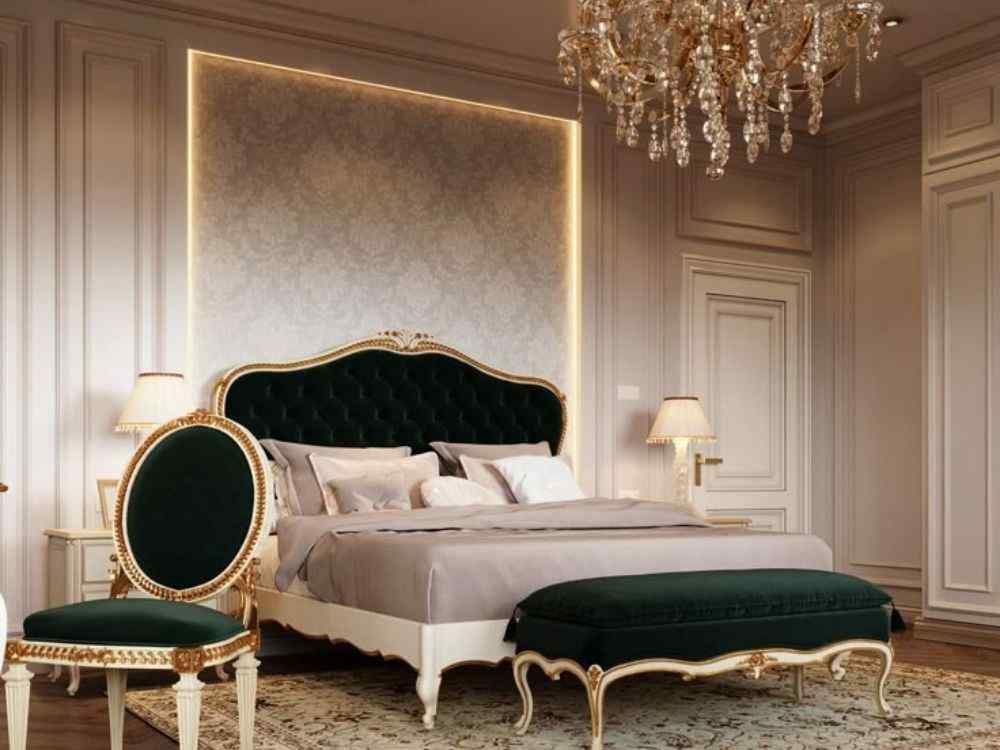 Phòng ngủ cổ điển với giường đầu bọc nhung xanh đậm, đèn bàn vàng, tường ốp phào chỉ tinh xảo