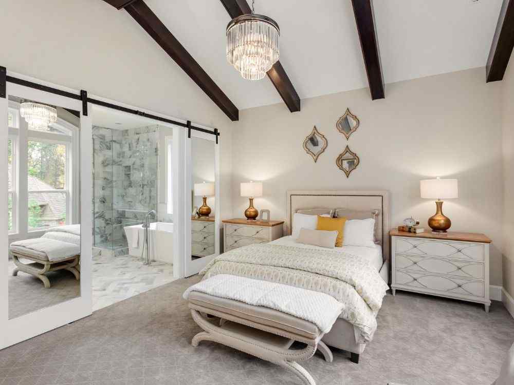 Phòng ngủ hiện đại với giường bọc nệm trắng kem, cửa trượt kính mở ra khu toilet lát đá marble