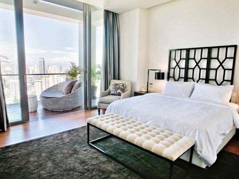 Phòng ngủ master có ban công rộng, giường trắng sang trọng, ghế thư giãn