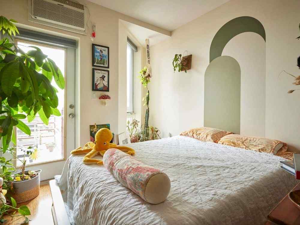 Phòng ngủ nhỏ ngập sáng với mảng tường vẽ hình vòm xanh, giường trắng