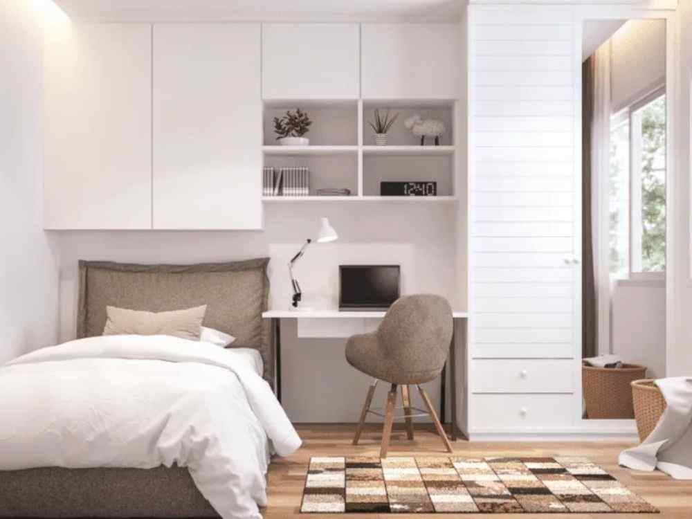 Phòng ngủ nhỏ với giường đơn, bàn làm việc và hệ tủ treo tường màu trắng tối giản