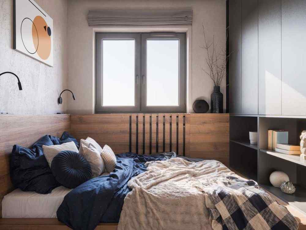 Phòng ngủ nhỏ với giường gỗ áp tường, chăn xám, kệ sách