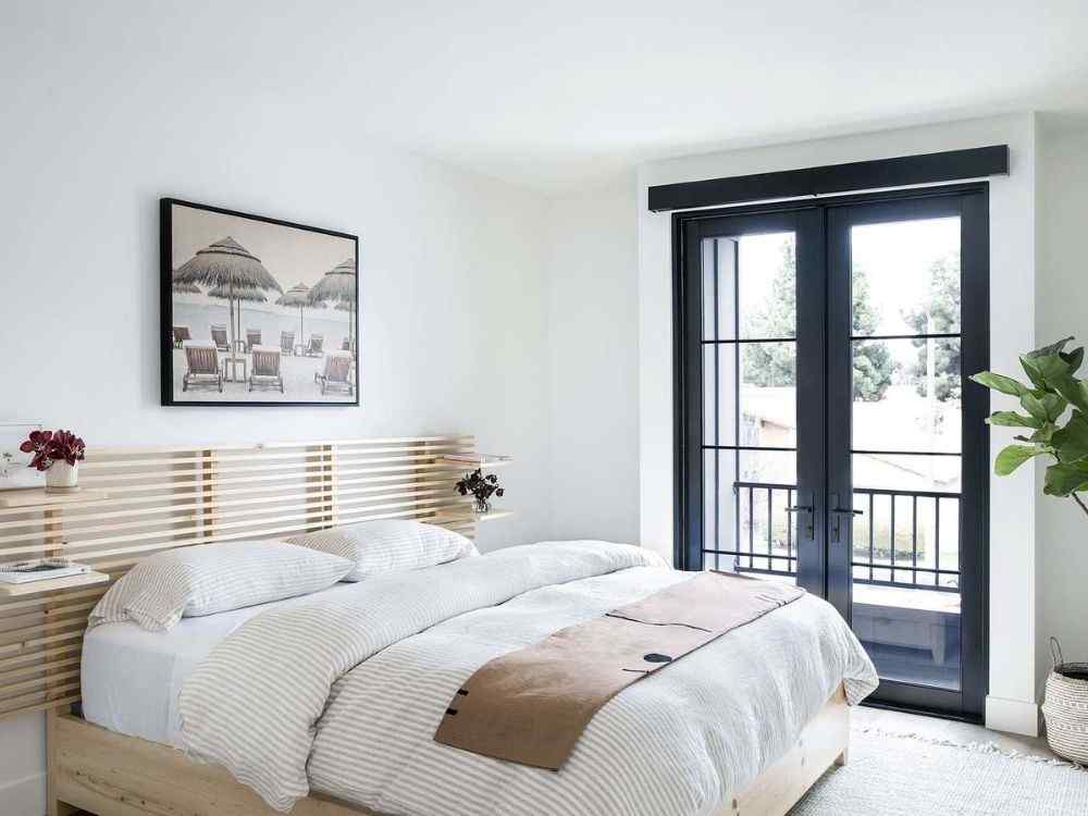 Phòng ngủ phong cách hiện đại, đầu giường nan gỗ, cửa kính đen khung lớn, gam màu sáng, cây xanh trang trí