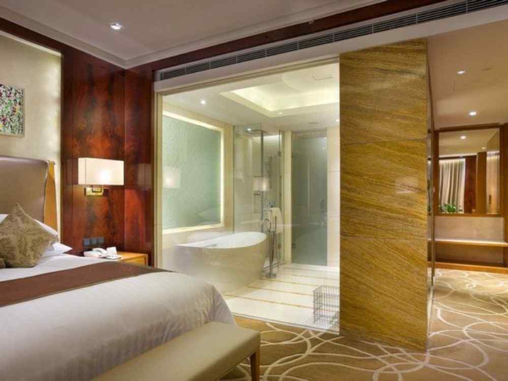 Phòng ngủ sang trọng với tường gỗ nâu bóng, giường đôi, toilet riêng ngăn kính trong suốt